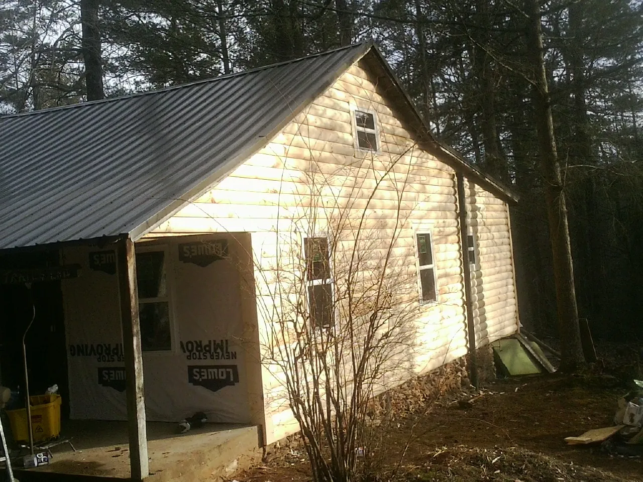 Log siding gable end under a dark metal roof edge in Milford